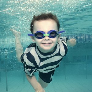 A young swimmer underwater in goggles.